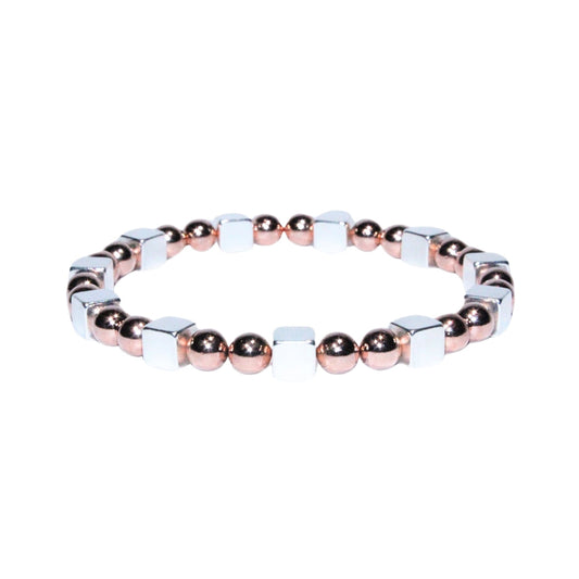 Photo sur fond blanc du bracelet en pierre d'aimant naturelle composé de cubes et de perles argentées et roses.