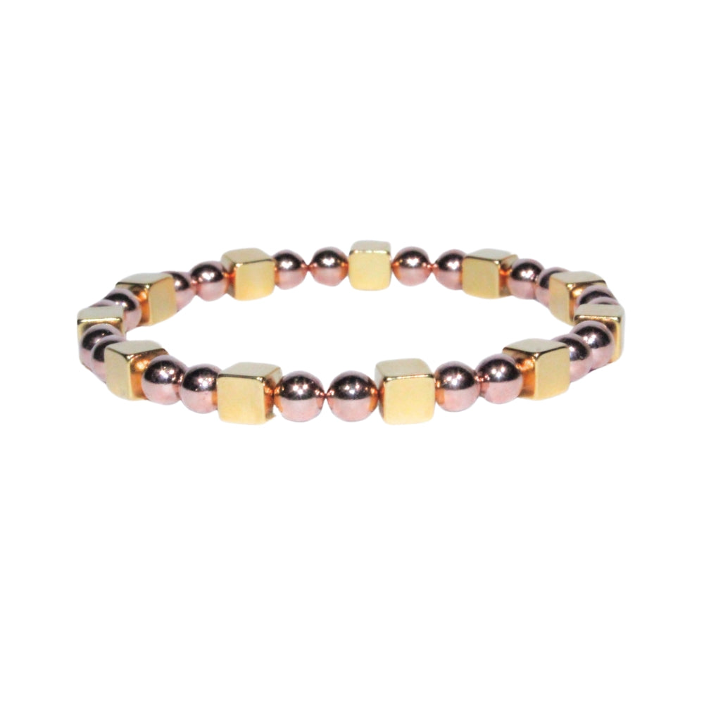 Photo sur fond blanc du bracelet en pierre d'aimant naturelle composé de cubes et de perles dorées et roses.