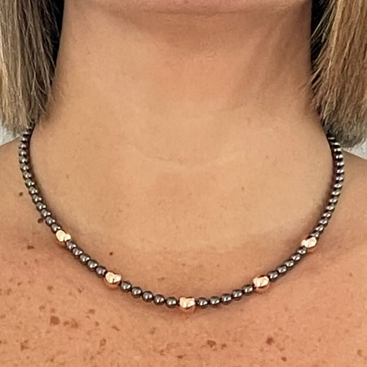 Photo sur fond blanc d'un collier en perles d'aimant pour femme aux couleurs nacre et rose.