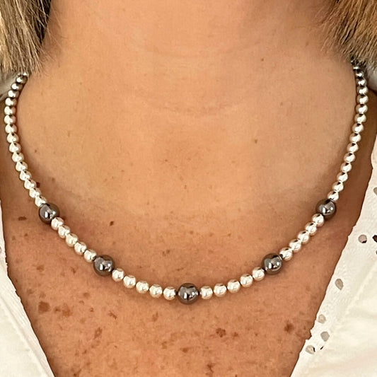 Photo sur fond blanc d'un collier en perles d'aimant pour femme aux couleurs argent et nacre.