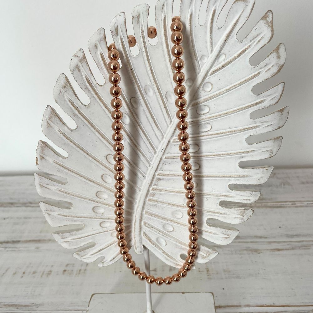 Photo sur fond blanc d'un collier en perles d'aimant pour femme de couleur rose.