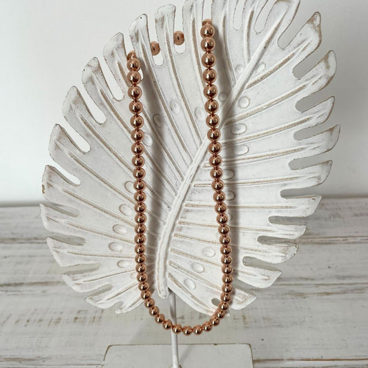 Photo sur fond blanc d'un collier en perles d'aimant pour femme de couleur rose.